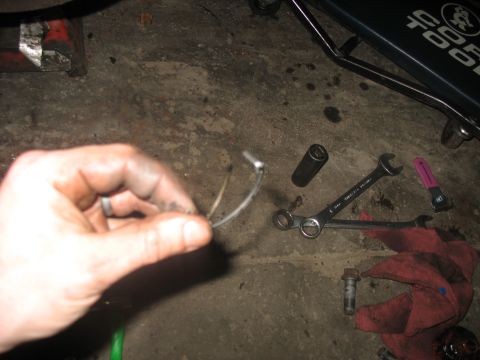 1995 Ford C-350 (Centurion Conversions) - Close-up of a hand holding a metal clip with wires, with tools scattered on the floor.