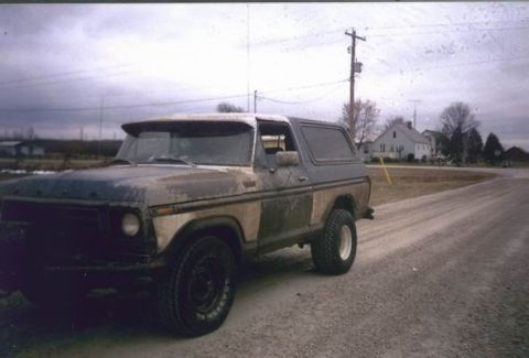 1978 Ford Bronco - This classic 1978 Ford Bronco sits on a gravel road with houses and trees in the background under a cloudy sky.
