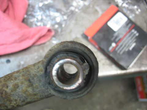 1995 Ford C-350 (Centurion Conversions) - Close-up of a worn suspension bushing on a rusty metal component, likely for a vehicle's front axle rebuild.