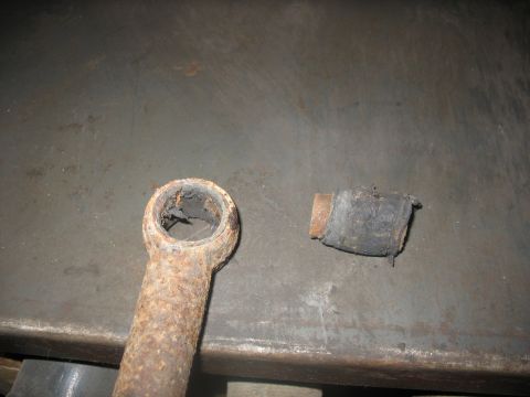 1995 Ford C-350 (Centurion Conversions) - A worn and rusted metal component, likely from a vehicle's suspension or steering system, is shown with its damaged rubber bushing.