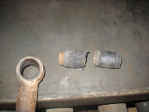 1995 Ford C-350 (Centurion Conversions) - Close-up of worn rubber bushings and a metal linkage, likely from a vehicle's front axle rebuild.