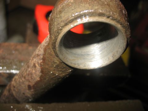 1995 Ford C-350 (Centurion Conversions) - A close-up view of a rusty metal pipe fitting, likely a vehicle part, with visible wear inside the interior.