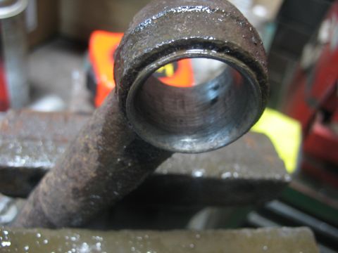 1995 Ford C-350 (Centurion Conversions) - A close-up view of a heavily worn metal component, likely a part from a vehicle's front axle, secured in a vise for inspection or repair.