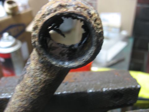 1995 Ford C-350 (Centurion Conversions) - This heavily corroded metal component is being held in a vise, showing significant damage and rust.