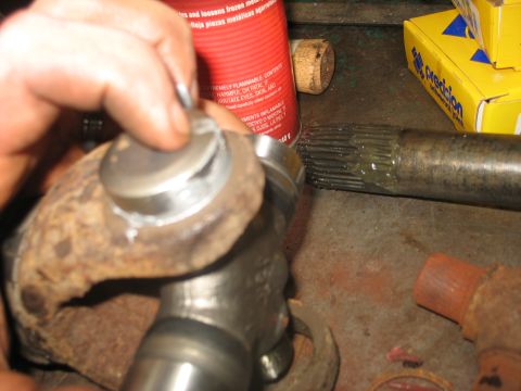 1995 Ford C-350 (Centurion Conversions) - Close-up of a greased driveshaft with splines and a u-joint assembly, likely for a vehicle's front axle rebuild.