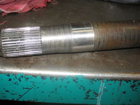 1995 Ford C-350 (Centurion Conversions) - A close-up view of a metal axle shaft, showing its splined end and a smooth, machined section.