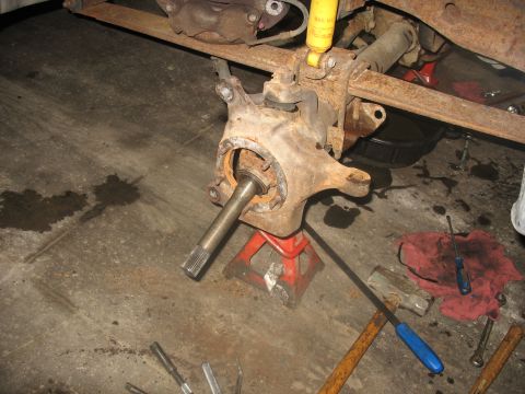 1995 Ford C-350 (Centurion Conversions) - Front axle assembly, likely from a Ford C-350, undergoing repair with tools scattered around.
