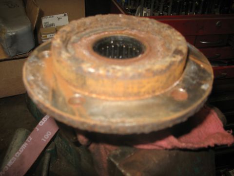 1995 Ford C-350 (Centurion Conversions) - A heavily rusted wheel hub assembly is clamped in a vise, with a red cloth underneath.