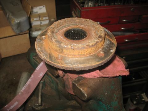 1995 Ford C-350 (Centurion Conversions) - A heavily rusted wheel hub assembly is clamped in a vise, with a piece of sandpaper nearby, suggesting repair or maintenance work.