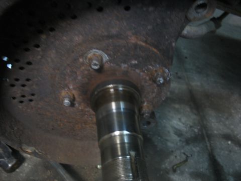 1995 Ford C-350 (Centurion Conversions) - Close-up of a rusty metal component with bolts and a shaft, likely part of a vehicle's axle assembly.