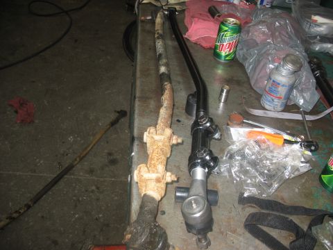 1995 Ford C-350 (Centurion Conversions) - Comparing a worn steering linkage with a new replacement part on a workbench.