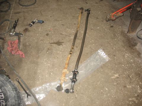 1995 Ford C-350 (Centurion Conversions) - Various automotive parts and tools are laid out on a garage floor, suggesting a repair or maintenance operation.