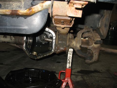 1995 Ford C-350 (Centurion Conversions) - Close-up of a vehicle's rear axle differential during a repair, with fluid draining into a pan.