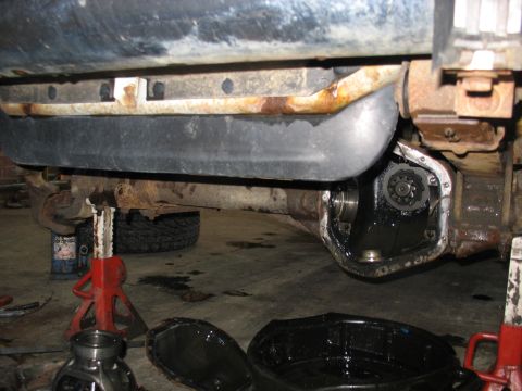 1995 Ford C-350 (Centurion Conversions) - The differential of a vehicle is exposed for maintenance, with tools and oil pans visible on the garage floor.
