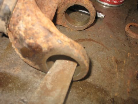 1995 Ford C-350 (Centurion Conversions) - A close-up view of a corroded metal part being filed, with a can of lubricant nearby.