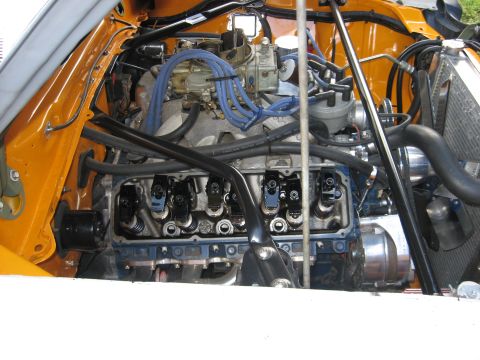 1978 Ford Mustang II - The engine bay of a car shows a V8 engine with exposed valve train components and various hoses and wires.