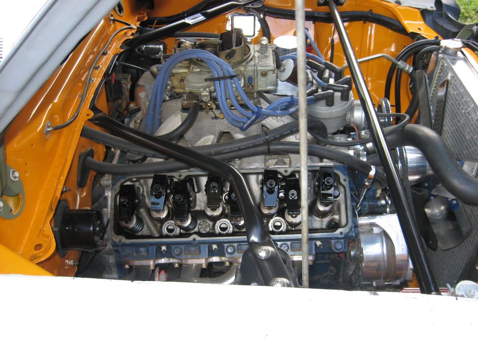 Close-up of a V8 engine with blue spark plug wires and a carburetor