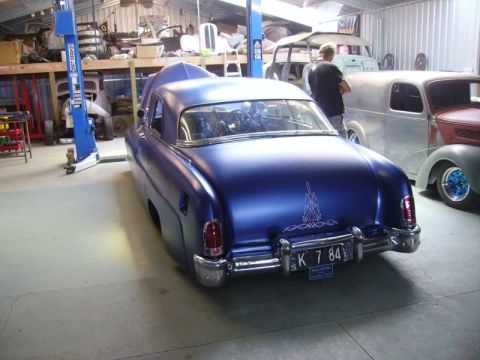 1969 Lincoln Continental - A custom blue sedan is parked in a garage next to other vehicles and a car lift.