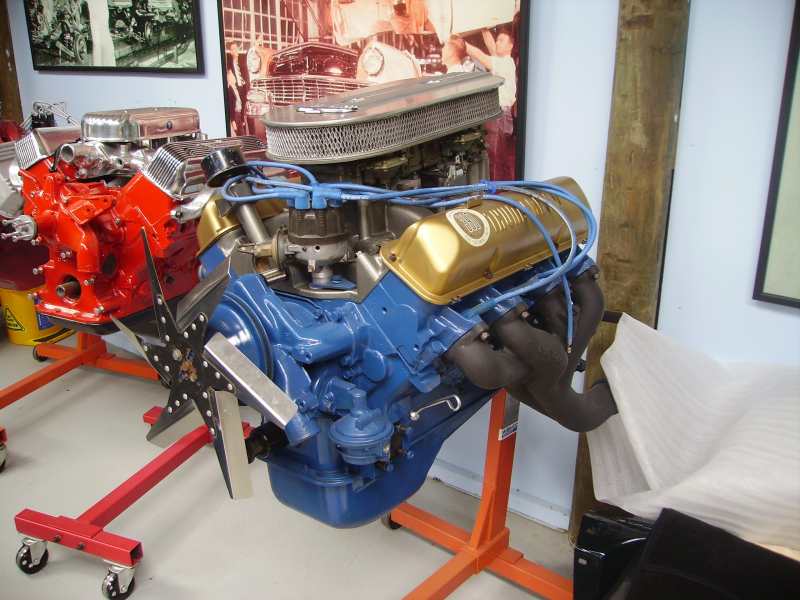 Blue and gold engine on an orange stand, with a red engine behind it