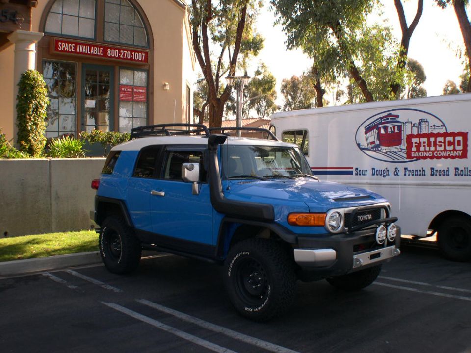 Blue 2007 Toyota FJ Cruiser parked next to a Frisco Baking Company truck