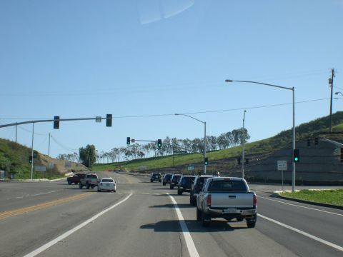 2007 Toyota FJ Cruiser - Vehicles wait at a traffic light on a sunny day, with a hill and trees in the background.