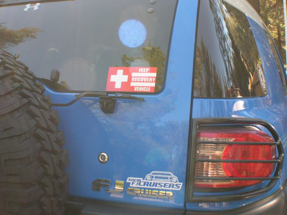 Blue 2007 Toyota FJ Cruiser rear with spare tire mounted, "SoCal FJ Cruisers" sticker, and a "Jeep Recovery Vehicle" sticker