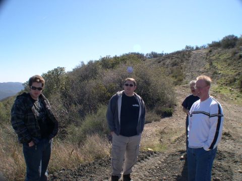 2007 Toyota FJ Cruiser - Four men are standing on a dirt road in a hilly, brush-covered area under a clear blue sky.