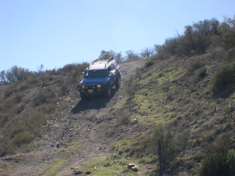 2007 Toyota FJ Cruiser - A blue 2007 Toyota FJ Cruiser navigates a steep, off-road trail under a clear blue sky.