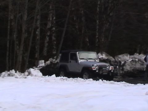 2005 Jeep Wrangler - A silver 2005 Jeep Wrangler is parked in a snowy environment with trees in the background.