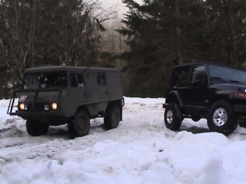 2005 Jeep Wrangler - Two off-road vehicles, a unimog and a Jeep Wrangler, are parked in a snowy wooded area.