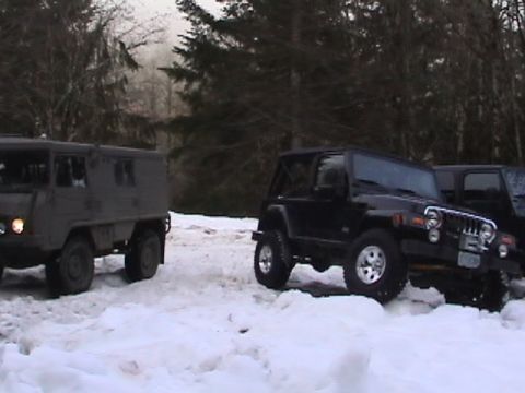 2005 Jeep Wrangler - Two off-road vehicles are parked in a snowy area with trees in the background.