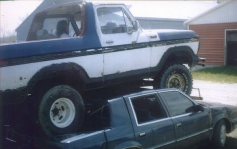 1978 Ford Bronco - A lifted 1978 Ford Bronco is parked on top of another vehicle.