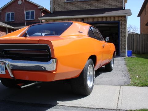 1991 Ford Bronco - Rear view of an orange 1969 Dodge Charger in a suburban driveway.