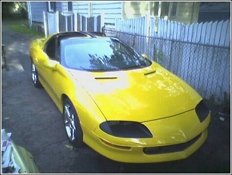 1991 Ford Bronco - This yellow 1993 Chevrolet Camaro Z28 is parked in a driveway next to a white fence.