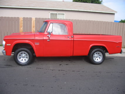 1991 Ford Bronco - Driver-side profile of a bright red vintage Dodge D-series regular-cab sweptline pickup with a long bed, chrome bumpers and mirrors, and ch…