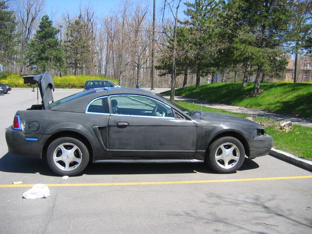 Primer-gray Mustang coupe in profile with trunk open and bumper removed
