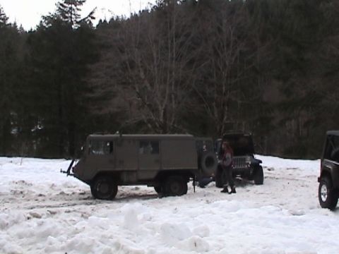 2005 Jeep Wrangler - Multiple vehicles, including a military truck and Jeeps, are parked in a snowy, wooded area.