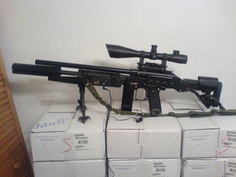 1985 Ford Bronco - A black sniper rifle with a scope and bipod is displayed on top of several white boxes.
