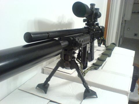 1985 Ford Bronco - A close-up view of a sniper rifle equipped with a scope and bipod, resting on a table.