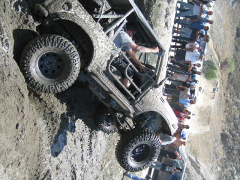 1987 Suzuki Samurai - A heavily modified 1987 Suzuki Samurai is stuck in mud, with a crowd watching the off-road adventure.
