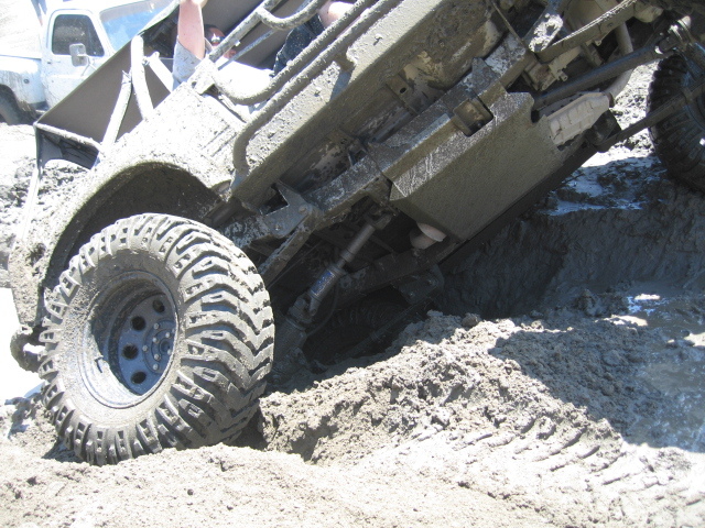Muddy off-road vehicle stuck in mud with another vehicle visible behind