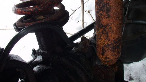 1979 Ford Bronco - Close-up view of heavily corroded suspension parts, including a coil spring and shock absorber.