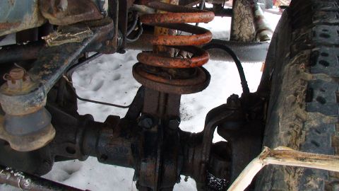 1979 Ford Bronco - Close-up view of the front suspension and tire of an off-road vehicle, partially covered in snow.