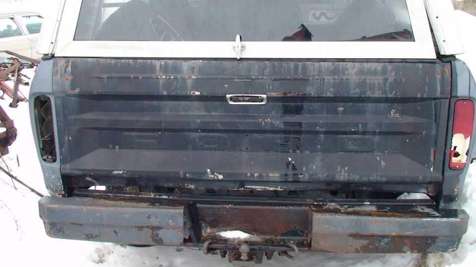 1979 Ford Bronco rear with tailgate down, showing the Ford lettering and a white camper shell