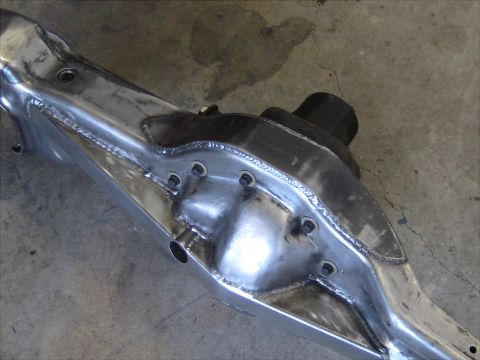 1996 Ford Bronco - Close-up view of a polished metal suspension component, likely a differential housing, showing intricate welding and bolt patterns.