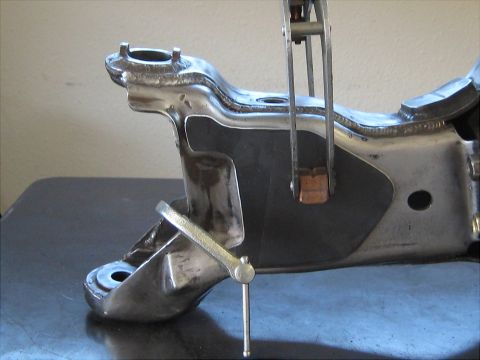 1996 Ford Bronco - A metal suspension part is secured with clamps on a dark surface.