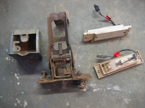 1992 Ford Mustang - Collection of assorted rusty car parts, including a metal bracket mechanism and two light fixtures with wiring.
