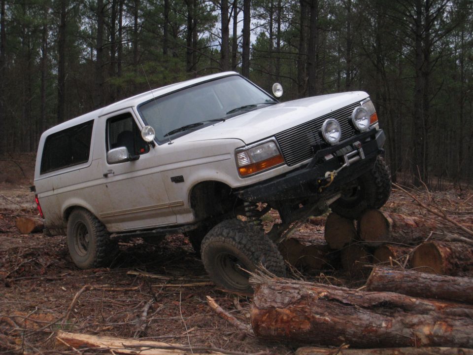 White Ford Bronco with off-road tires and bumper, angled on logs