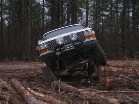 1996 Ford Bronco - This 1996 Ford Bronco navigates a challenging off-road course, climbing over fallen logs in a wooded area.