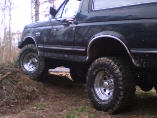 1990 Ford Bronco - 1990 Ford Bronco equipped with 33x12.50 Goodyear MTR tires navigating an off-road trail.